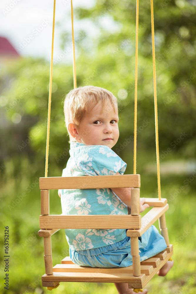 Handsome boy sitting on a swing. Looking back Handsome boy sitting on a swing. Looking back