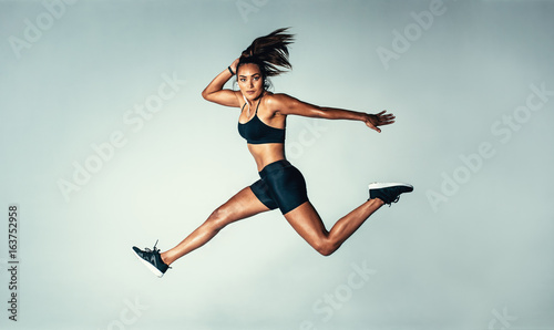 Female model in sports wear jumping in air photo