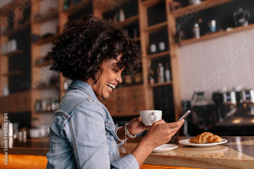 African woman cafe using mobile phone and smiling