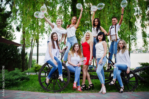 Fototapeta Naklejka Na Ścianę i Meble -  Comany of young women posing outside with inflated condoms at bachelorette party.