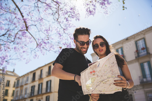 Tourist couple looking at map standing outside