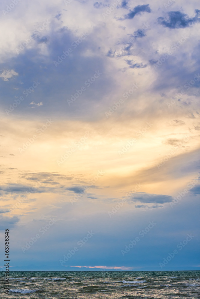 Fototapeta premium bird flying over surface of green sea waves with mountains on background 
