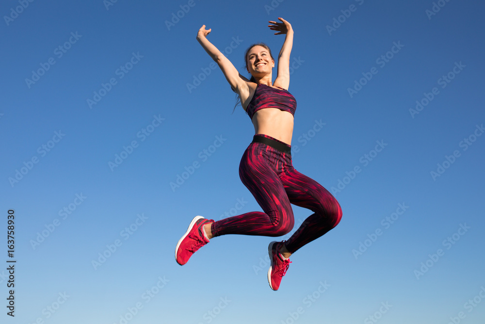 Isolated of young happy sportswoman in sportswear jumping and flying at blue sky background. She enjoying summer. Healthy lifestyle concept, sport activity. Isolated of young happy sportswoman in sportswear jumping and flying at blue sky background. She enjoying summer. Healthy lifestyle concept, sport activity.
