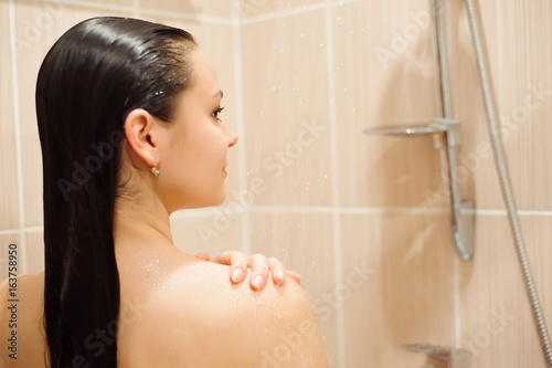 Girl showering in shower cabin cubicle enclosure. Young woman taking care of hygiene in bathroom.