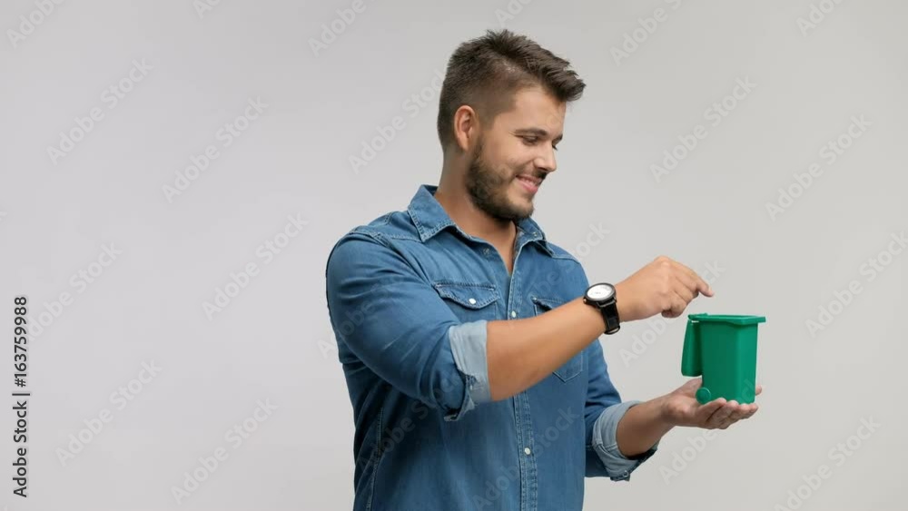 Young man throwing a piece of garbage in a small bin Young man throwing a piece of garbage in a small bin