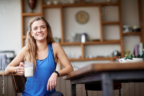 Young woman at kitchen table with smoothie photo