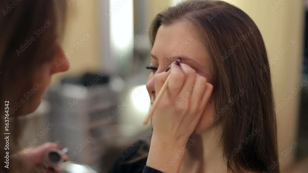 Makeup artist making professional makeup for young woman in beauty studio. Makeup artist making professional makeup for young woman in beauty studio.