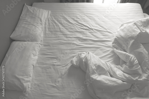 Messy white bedding sheets and pillows. black and white tone