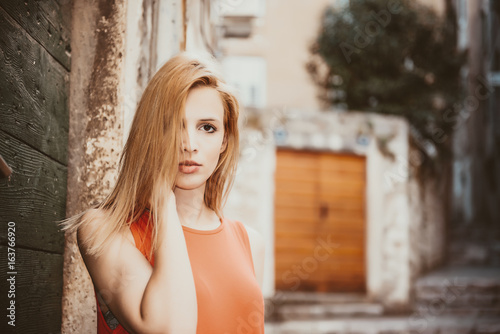 Outdoor close up portrait of model woman in fashionable red dress.City lifestyle.City lifestyle.Female fashion concept.Retro and vintage filter and colors effect used. © epic_images