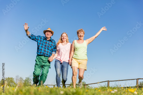 Grandparents with granddaughter running happy on the field