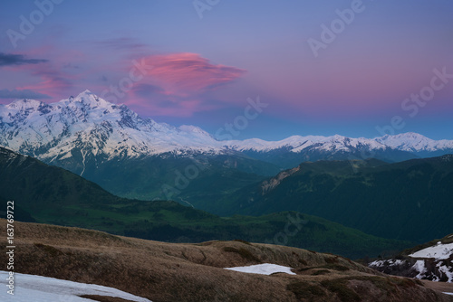 Colorful red clouds float over beautiful snow-capped peak