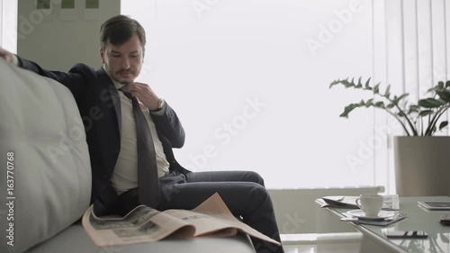 The businessman reads a newspaper in vip lounge hall in the airport photo