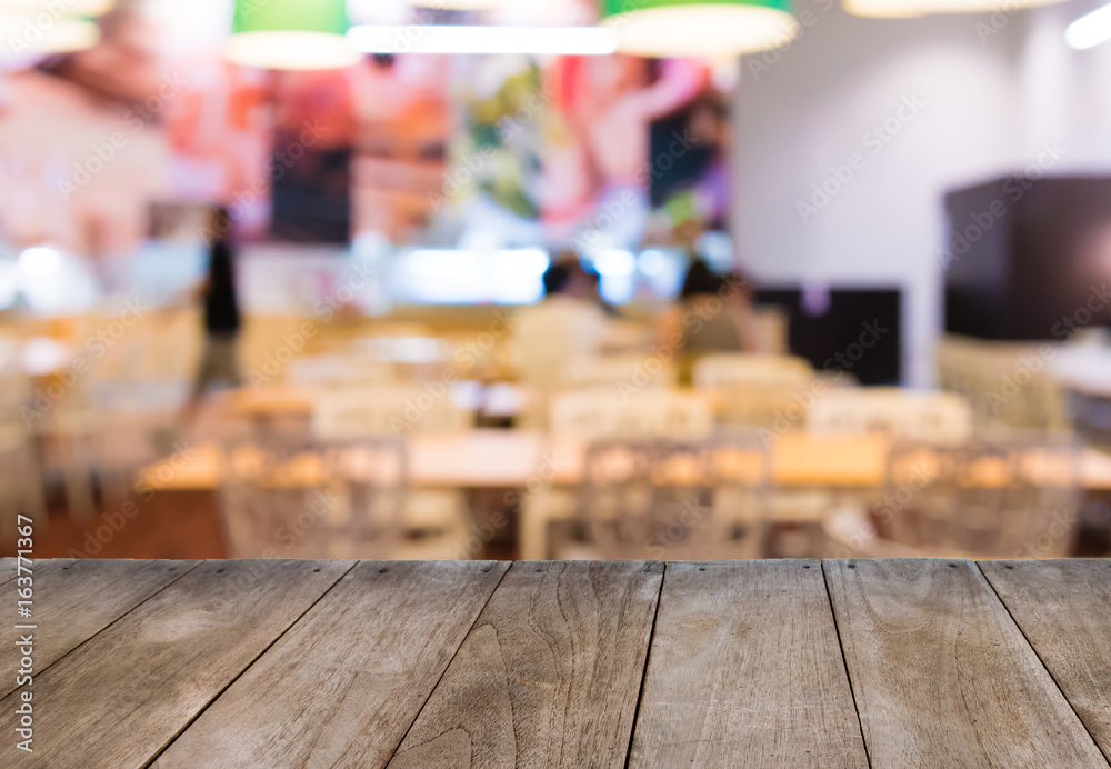 Empty wooden table in front of blurred background of restaurant tables and chairs