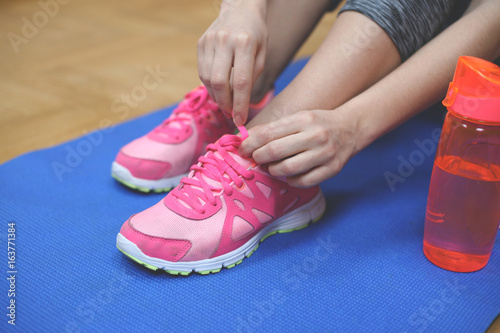  Close up of woman hand. Woman tying the shoelaces of her fitness shoes.