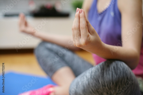 Woman meditating. Young fit woman doing sport exercises at home. Close up.