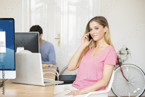 Manage my business. Shot of a confident young businesswoman using laptop and making call while managing her small business. 