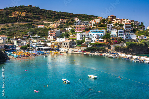Bali, Island Crete, Greece, Sunny day scenery scenery with mountains, Mediterranean sea, flowers and pier with boats and ship for walking tourists in the sea near village Bali