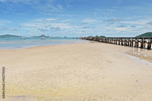 Sea and white sand beach under the blue sky and the old bridge for boat fishing.