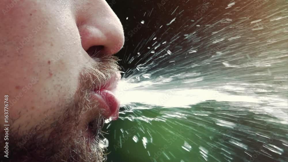 young man splash and splatter water out of his mouth - super slow