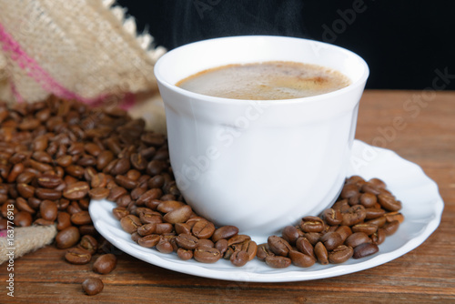 Cup with coffee on the table next to coffee beans