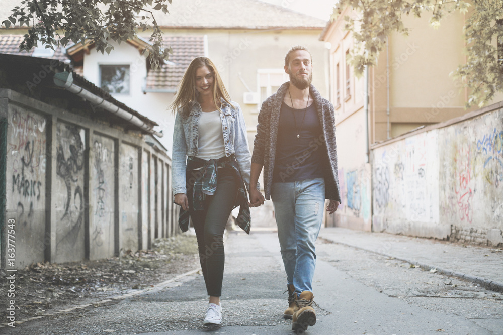 Couple holding hands outdoors. Young couple waling on the street.