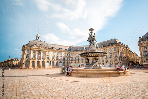 View on the famous La Bourse square with fountain in Bordeaux city, France. Long exposure image technic with motion blurred people and clouds photo
