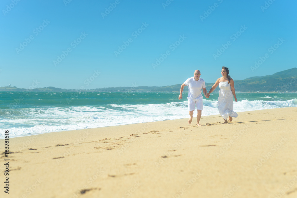 Young romantic couple running on the beach holding hands Young romantic couple running on the beach holding hands