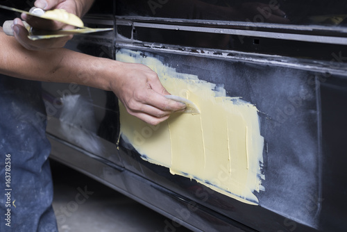 Photography Auto body repair series: Mechanic applying putty filler