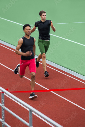 Group of athlete men run on running track outdoors © Drobot Dean
