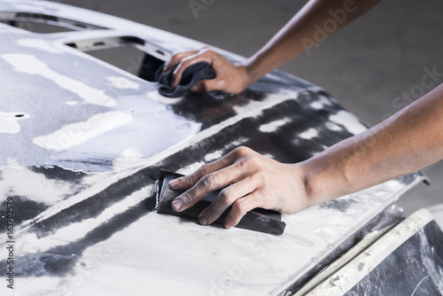 Auto body repair series: Closeup of mechanic wet-sanding car bonnet