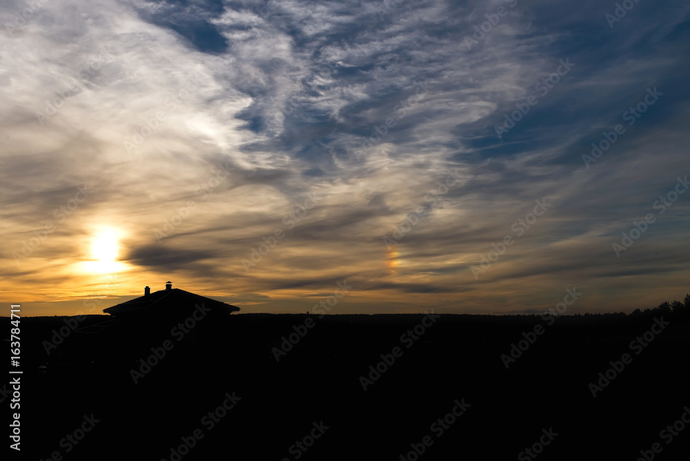 Sunset rainbow. A silhouette of country house against sunset sky.