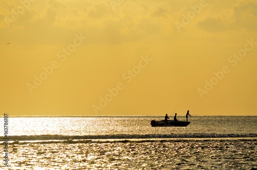 coucher de soleil mer océan eau bateau pêcheur pêche jaune silhouette 