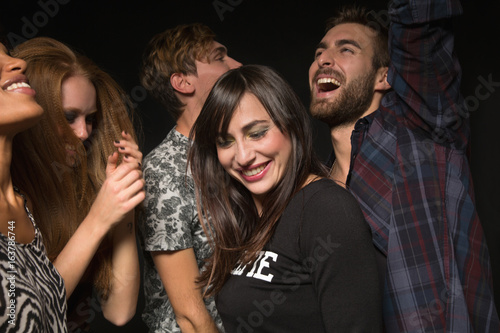 Happy young friends dancing inside club photo