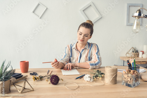 Slika na platnu attractive female decorator working at table with dry flowers