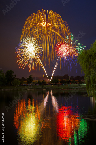 Independence Day Fireworks Reflected in Water with a willow tree in the foreground