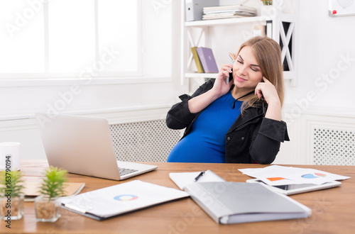Pregnant business lady at work talking on phone