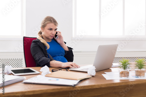 Pregnant business lady at work talking on phone © Prostock-studio