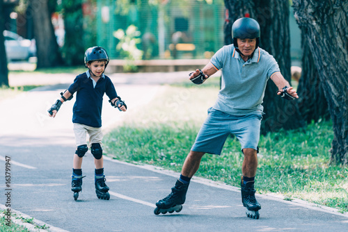 Grandfather teaching grandson roller skating in the park photo
