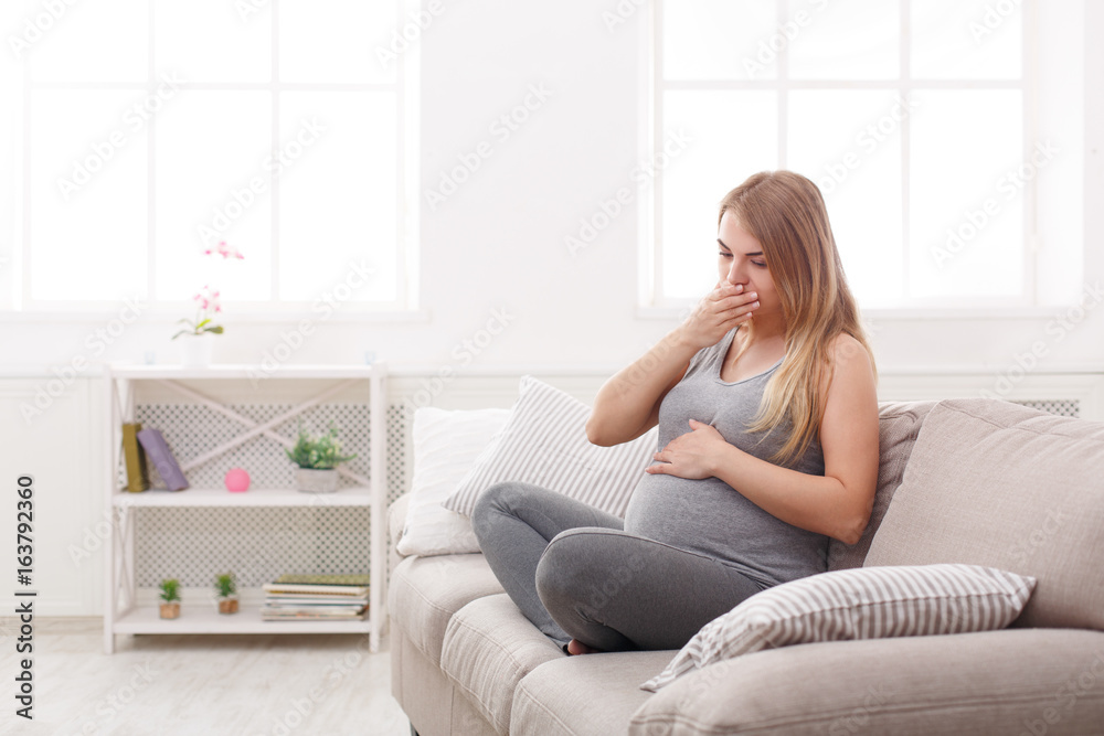 Young vomiting woman sitting on sofa