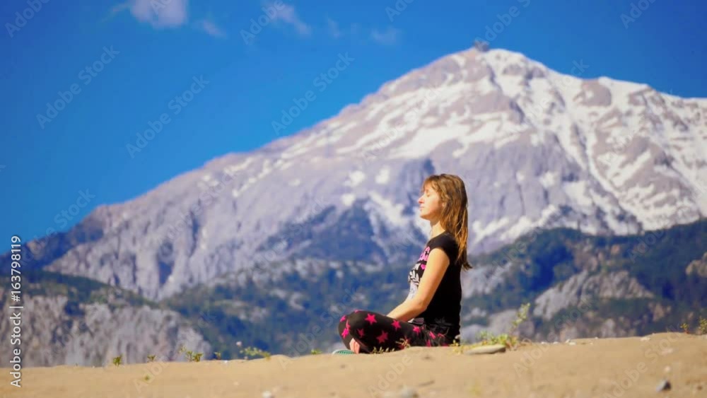 Young woman sitting calm cross-leged on the sand Young woman sitting calm cross-leged on the sand