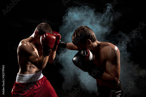 Photo Two professional boxer boxing on black smoky background,