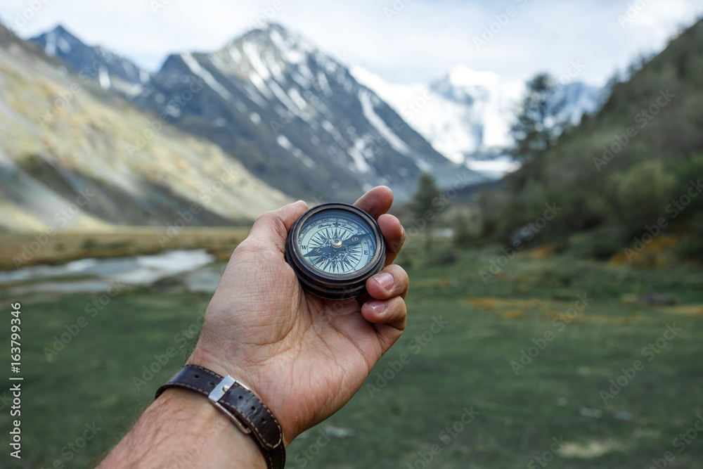 Hand Holding Compass in background mountain Hand Holding Compass in background mountain
