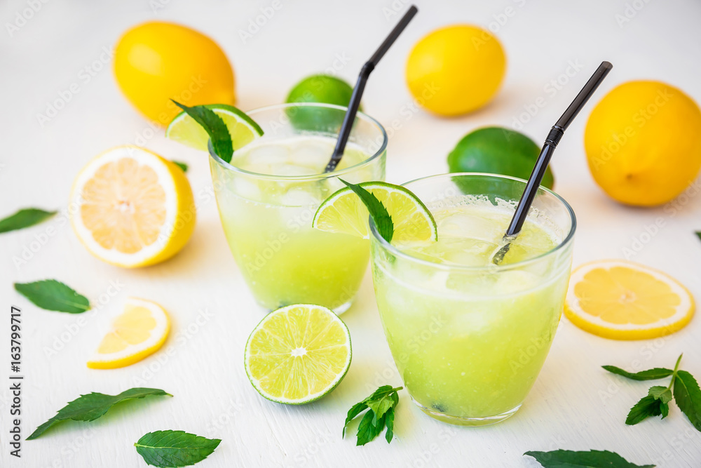 Fresh citrus lemonade with limes and lemons in glasses on white table Fresh citrus lemonade with limes and lemons in glasses on white table