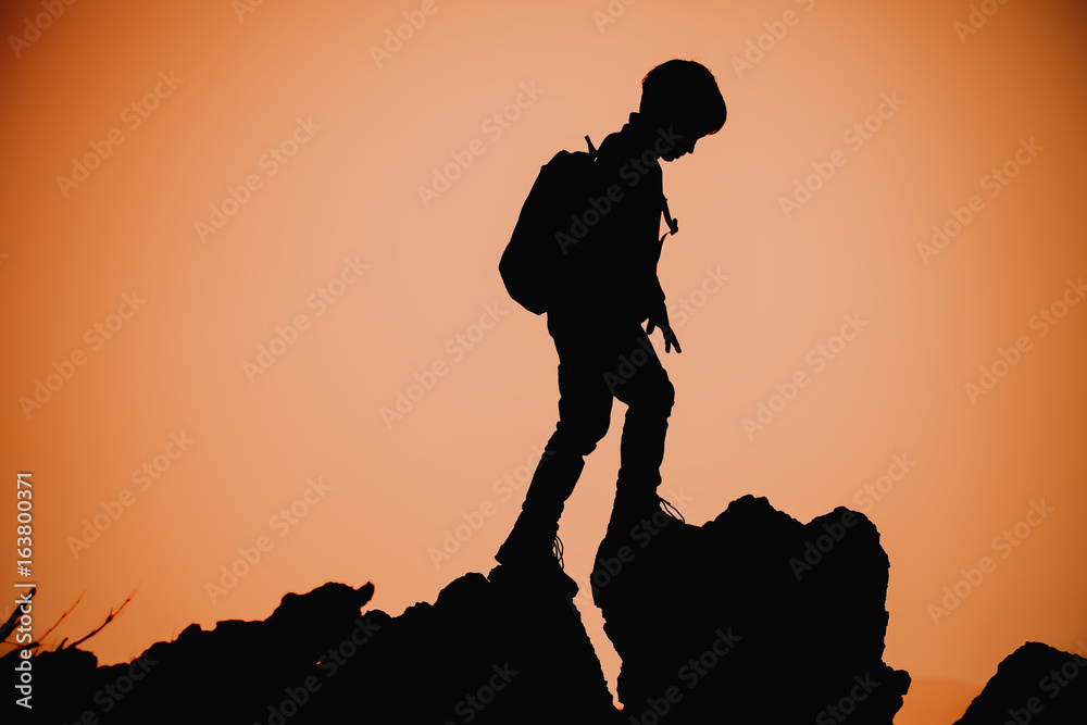 Silhouettes of little boy hiking at sunset