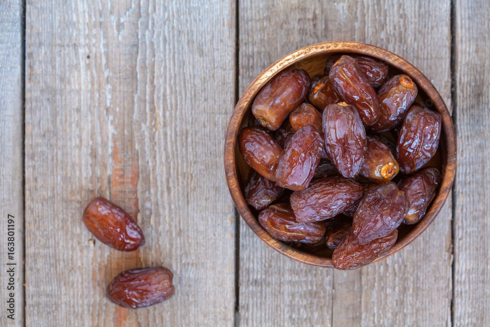 Fresh royal medjool dates in wooden bowl. Love for a healthy vegan food concept. Fresh royal medjool dates in wooden bowl. Love for a healthy vegan food concept.