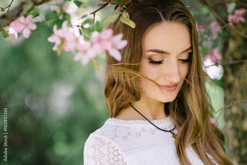 Young beautiful girl walking in a beautiful park among the flowering trees Young beautiful girl walking in a beautiful park among the flowering trees