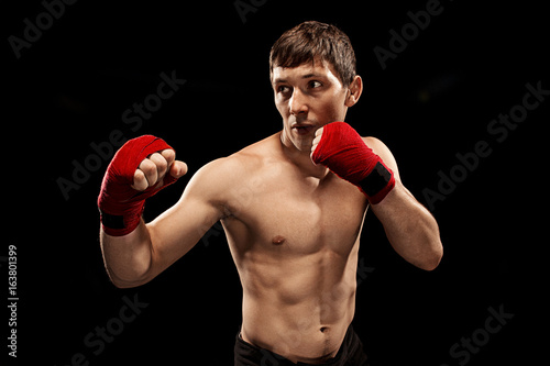 Male boxer boxing in punching bag with dramatic edgy lighting in a dark studio © master1305