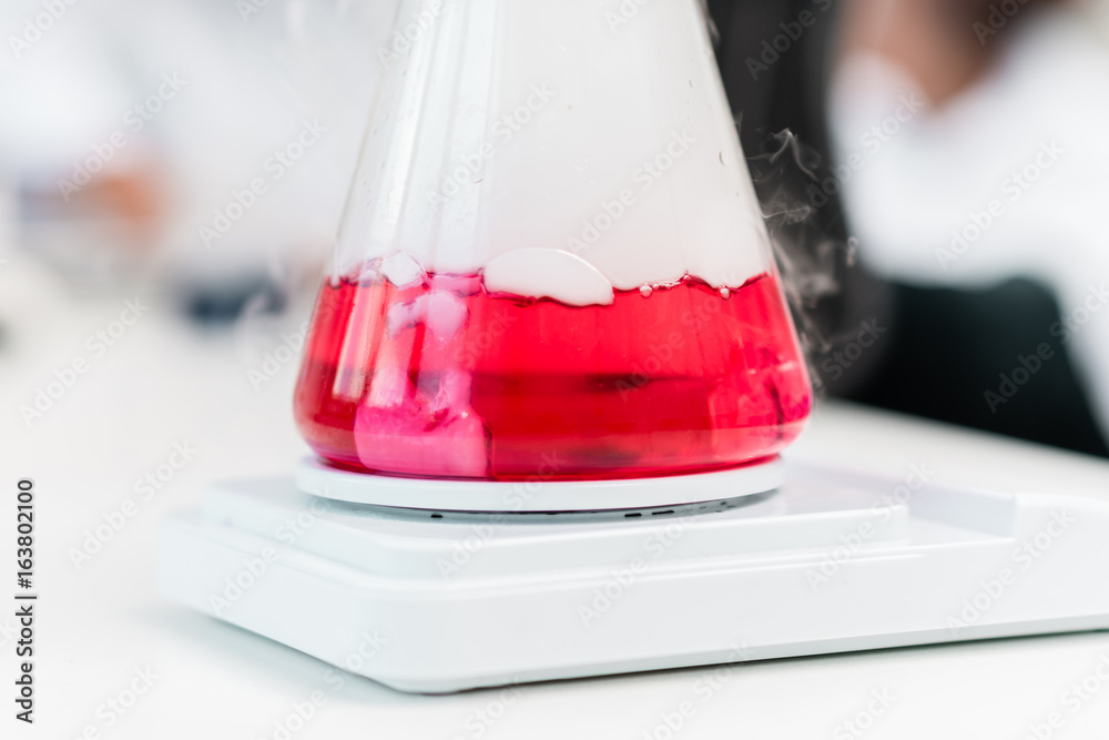 Close-up view of flask with red reagent and steam on electronic scales Close-up view of flask with red reagent and steam on electronic scales