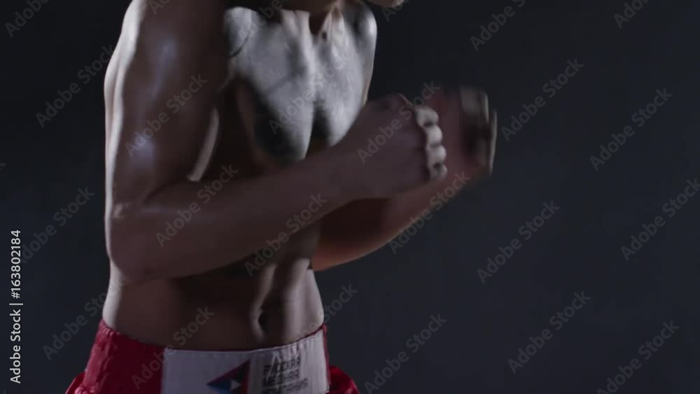 Man with tattoos boxing in a dark room with smoke. Aggressive shirtless ...