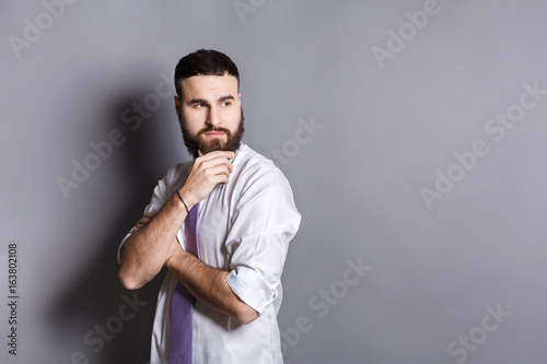 Pensive bearded businessman with hand on chin